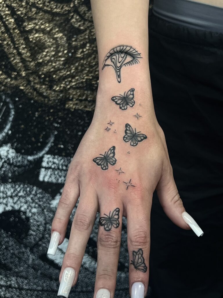 Sofortige Hautkunst: Schmetterlinge und Sterne schmücken die Hand und Finger. Einzigartiges Flash-Tattoo-Design für einen zauberhaften Look.